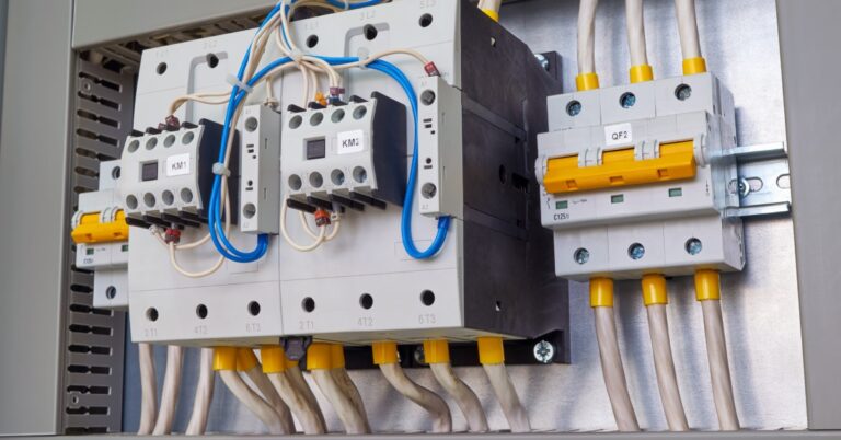 Two electrical contactors and two circuit breakers inside a steel electrical cabinet. All devices are hooked up with cables.