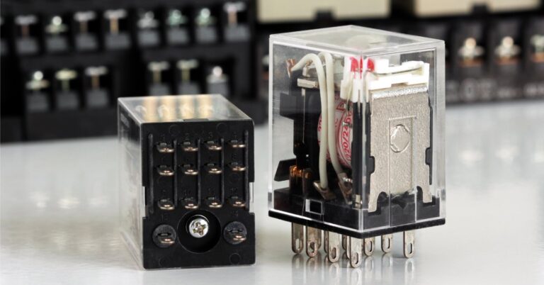 Two electrical auxiliary relays placed on a table, one lying on its side and the other standing upright on its prongs.