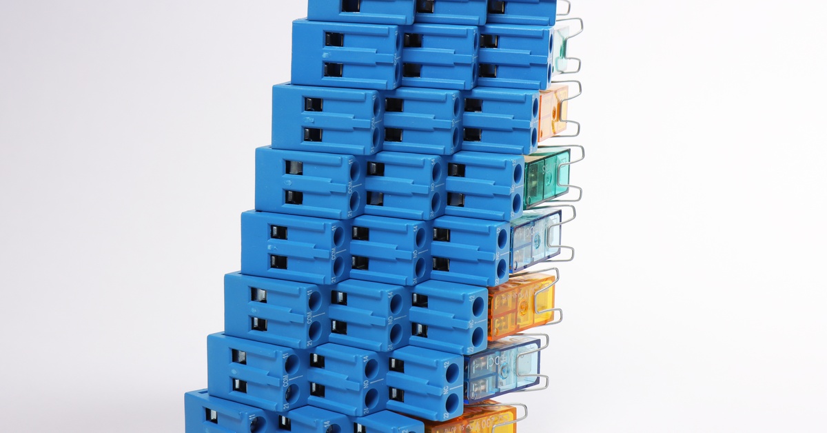 A group of electromagnetic relays for controlling electrical loads stacked on top of one another against a white background.