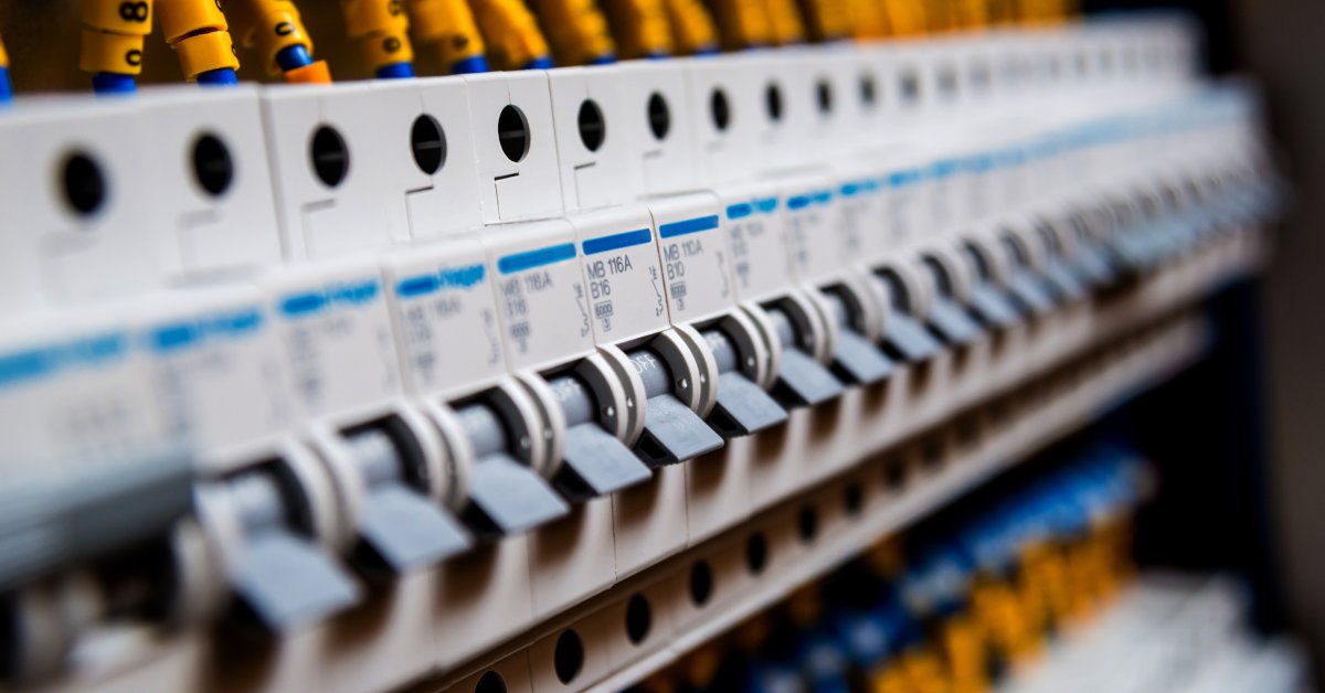 A row of electrical circuit breakers with labeled switches aligned in a control panel for power distribution.