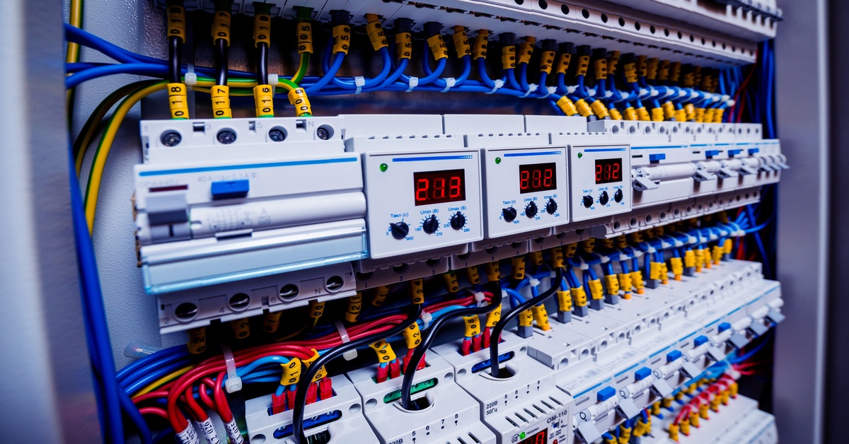 Industrial electrical panel with circuit breakers, wiring, and digital displays for power distribution and control.