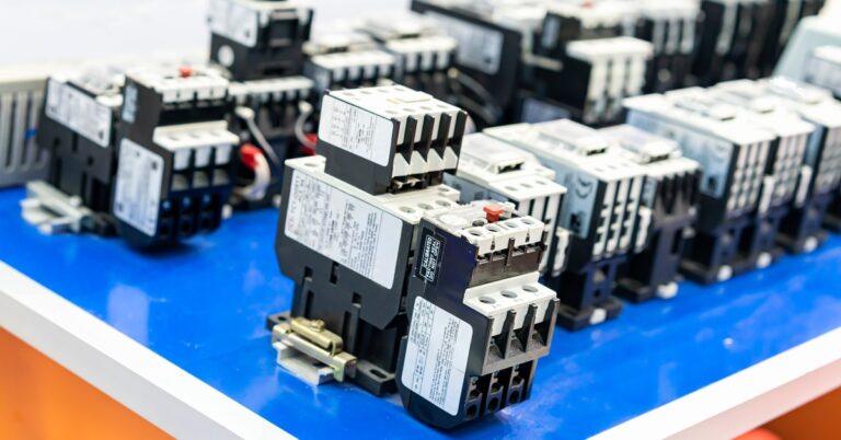 Industrial electrical contactors displayed on a blue surface showing various sizes and configurations for electrical applications.